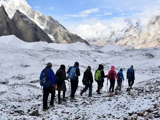 Trekkers on the Baltoro glacier with K2 in the distance